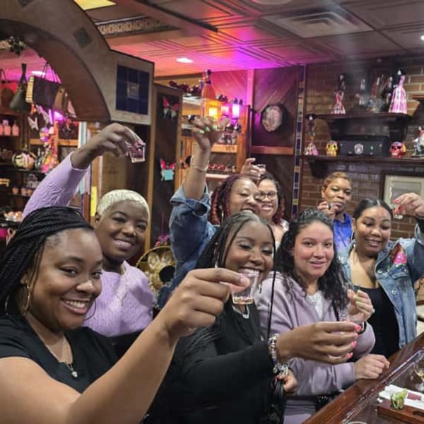 Smiling women at Casa Juarez Mexican Town raising shot glasses in a lively bar setting.