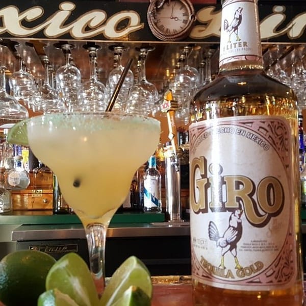 A Casa Juarez Mexican Town margarita and a bottle of Giro Tequila Gold on a bar.