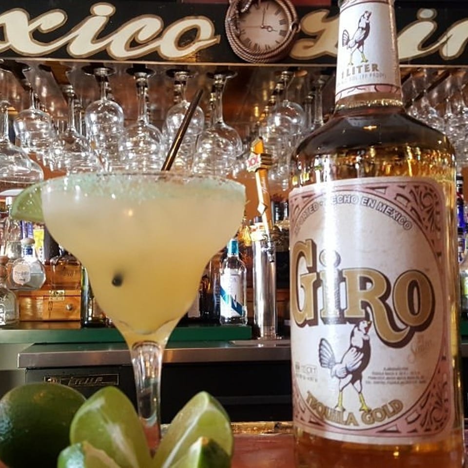A Casa Juarez Mexican Town margarita and a bottle of Giro Tequila Gold on a bar.