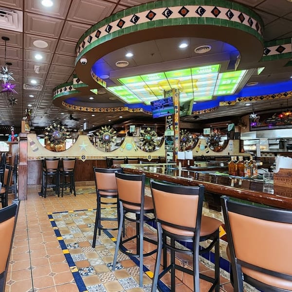The vibrant interior of Casa Juarez Mexican Town, featuring a colorful bar with stools and decorative lighting.
