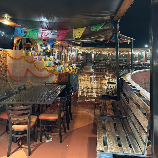 Outdoor patio at Casa Juarez Mexican Town decorated with colorful papel picado and marigold garlands.