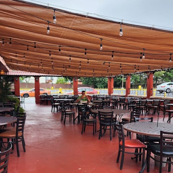 Casa Juarez Mexican Town's outdoor patio with red flooring, many tables, and string lights overhead.